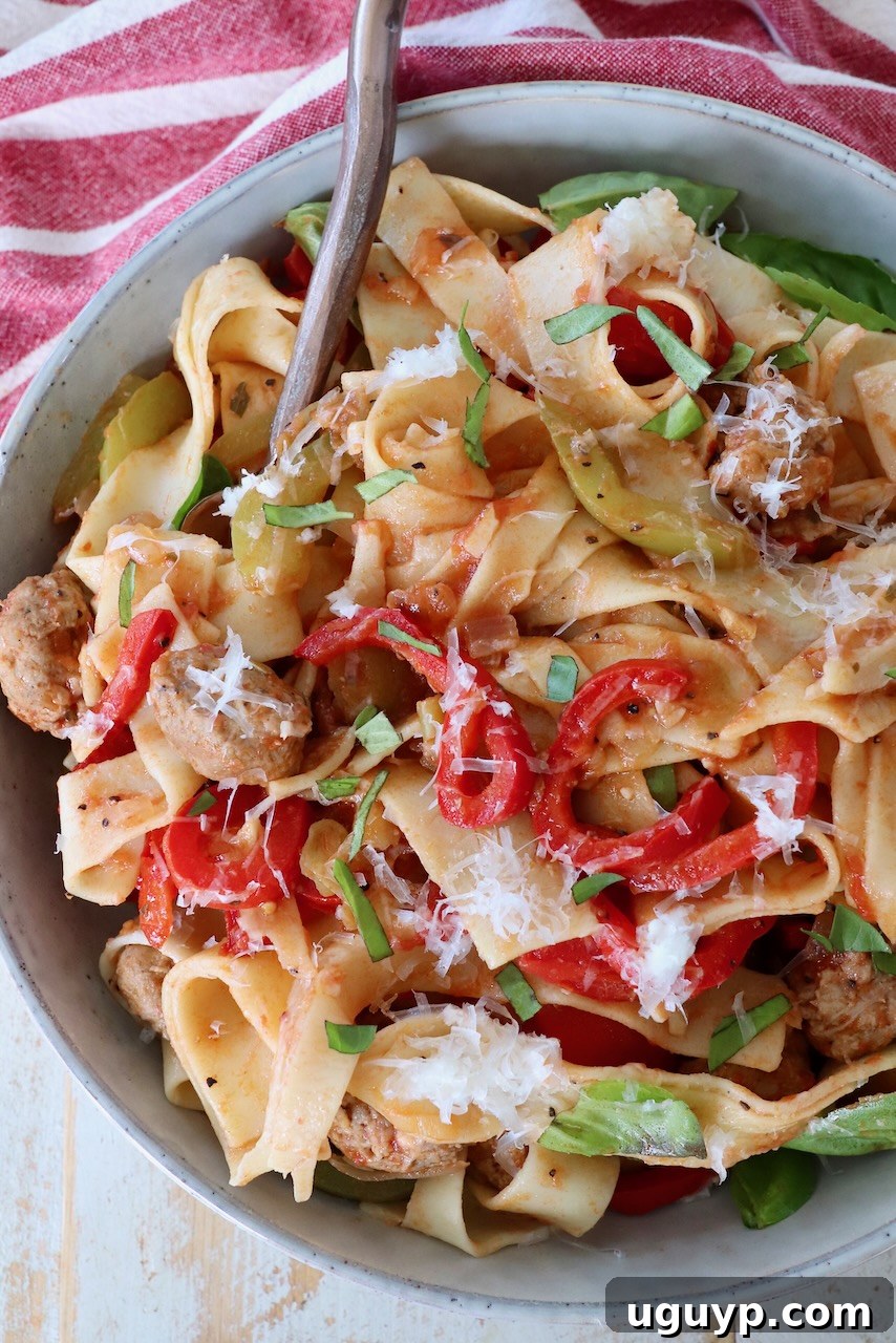 A fork lifts a generous portion of cooked Italian Drunken Noodles from a bowl, showcasing the vibrant ingredients.