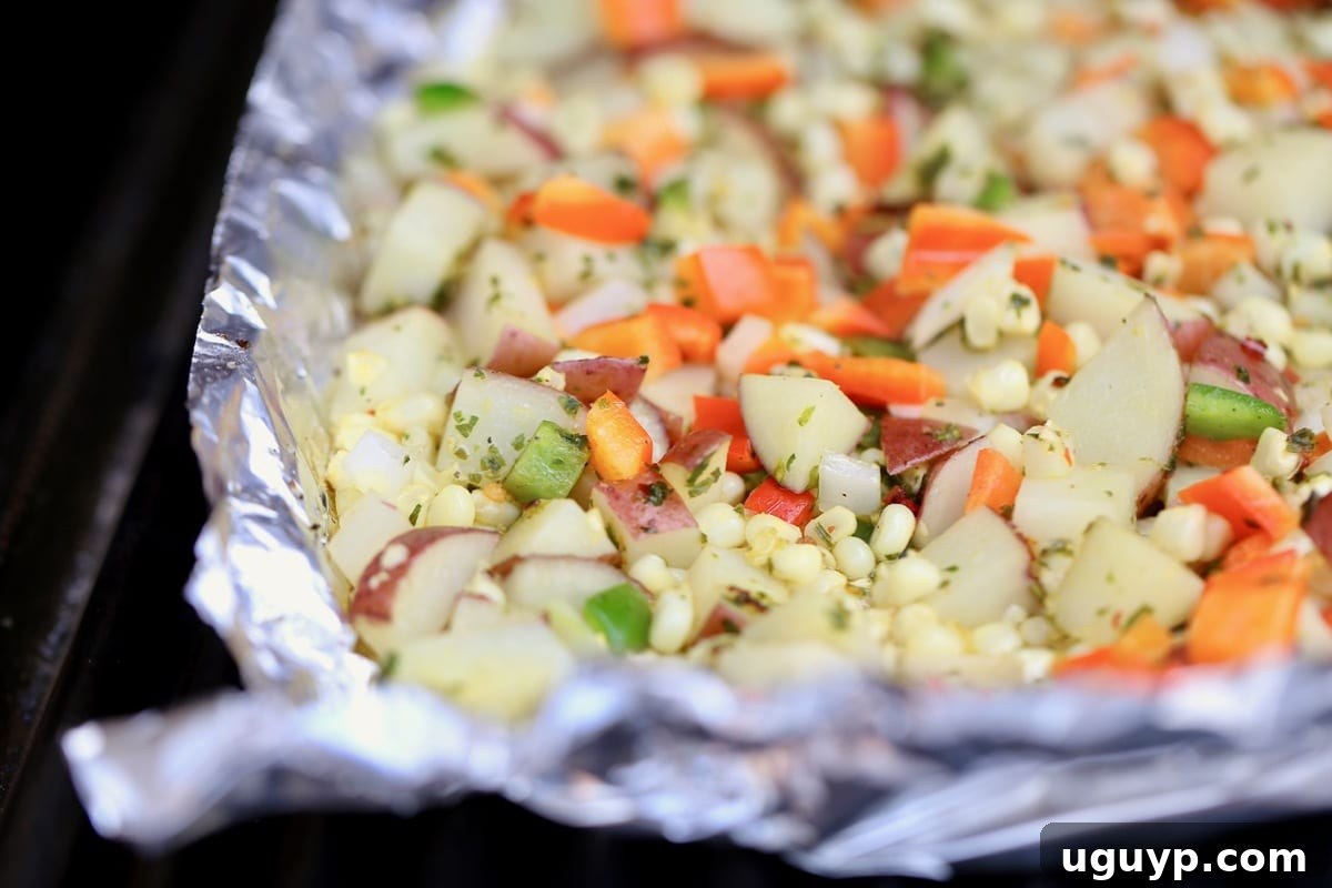 Diced potatoes, colorful bell peppers, sliced onions, and minced garlic simmering in a heavy-duty foil basket on a hot grill.