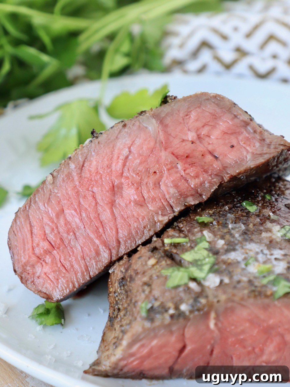 sous vide steak sliced in half on plate, perfectly cooked medium-rare