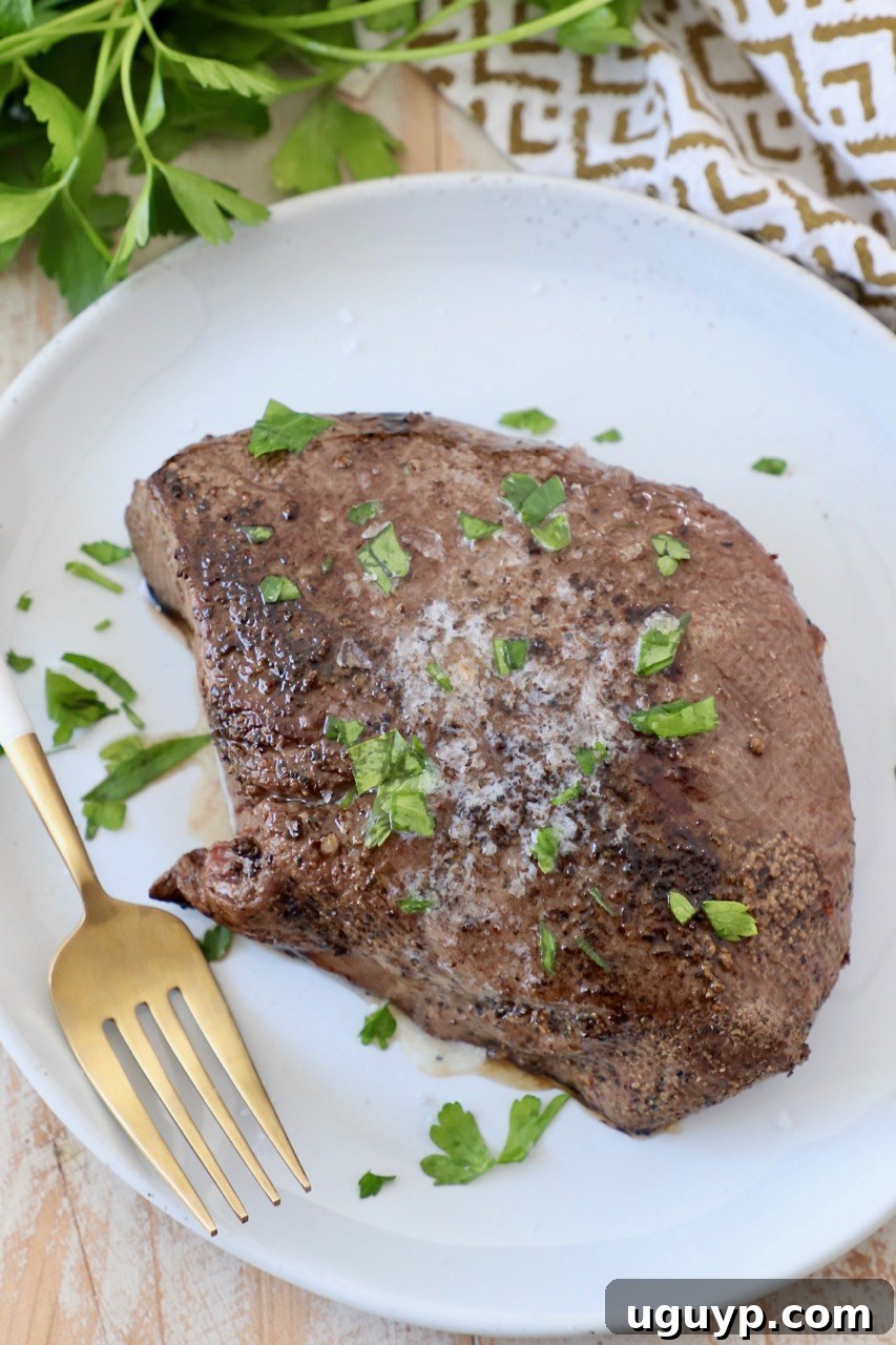 Cooked sous vide steak on a plate with a fork, showing tender interior.