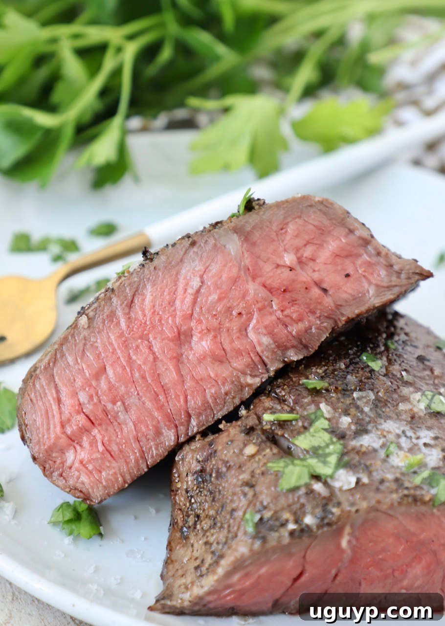 Perfectly medium-rare sous vide steak sliced on a plate, garnished with fresh parsley.