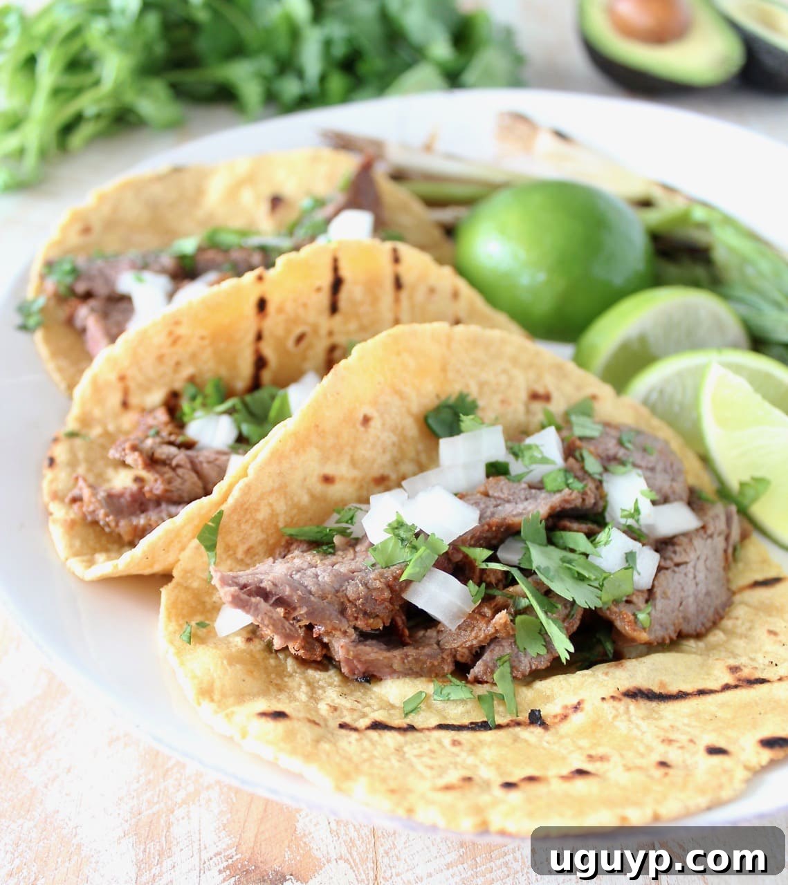 Vibrant Carne Asada Tacos garnished with fresh limes, red onions, and cilantro, promising an authentic Mexican culinary experience.