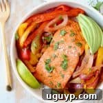Baked Salmon with Fajita Seasoned Bell Peppers and Onions in Bowl with Sliced Avocado and Lime Wedge