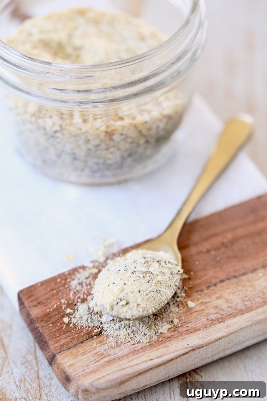 Homemade French Onion Dip Mix in a small gold spoon on a rustic wooden and marble cutting board, with a mason jar of the mix in the background, highlighting the ease of making and storing.
