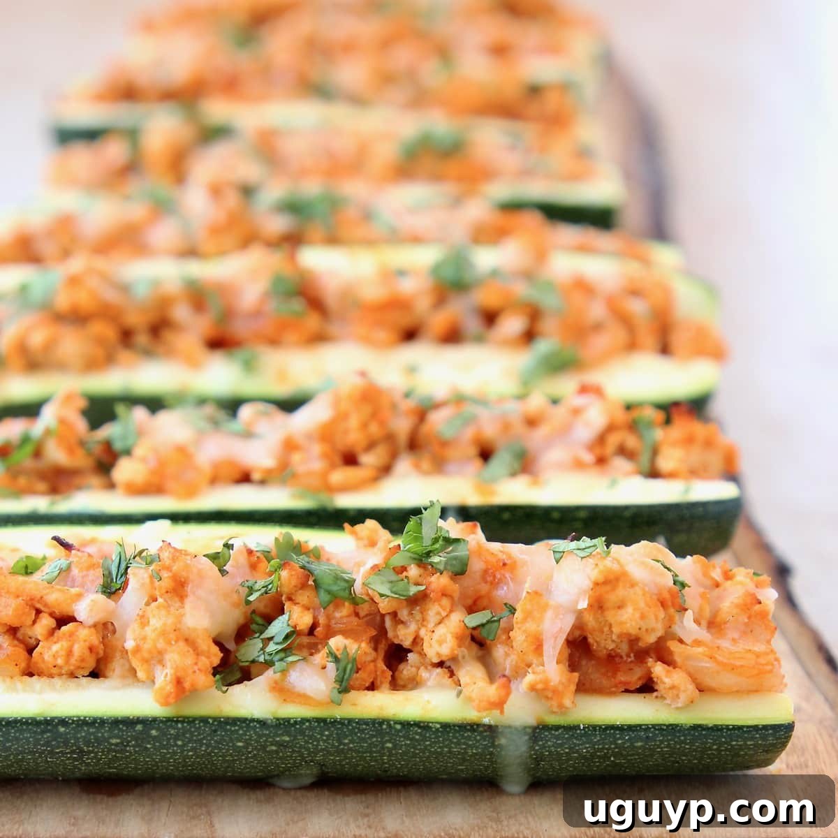 Buffalo Chicken Zucchini Boats with Pepper Jack Cheese and Cilantro on a wooden surface.