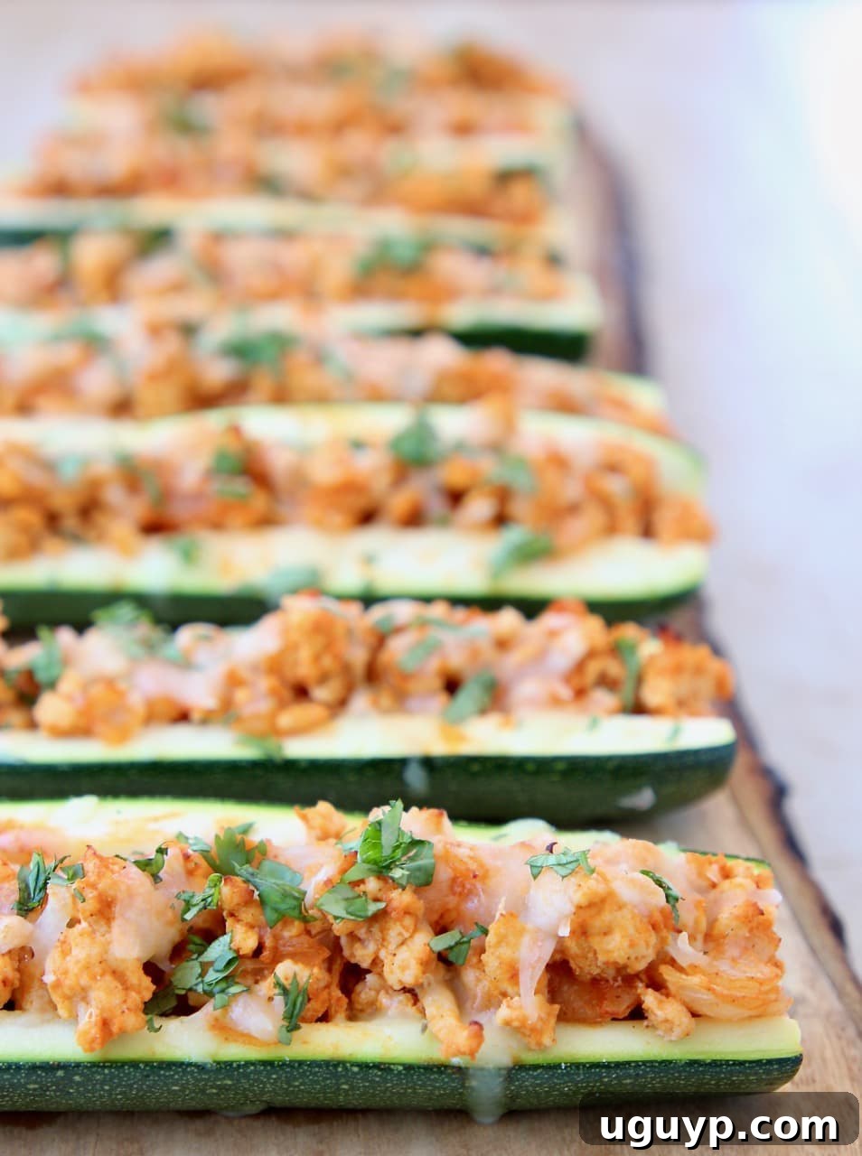Buffalo Chicken Zucchini Boats on Wood Cutting Board with Fresh Cilantro