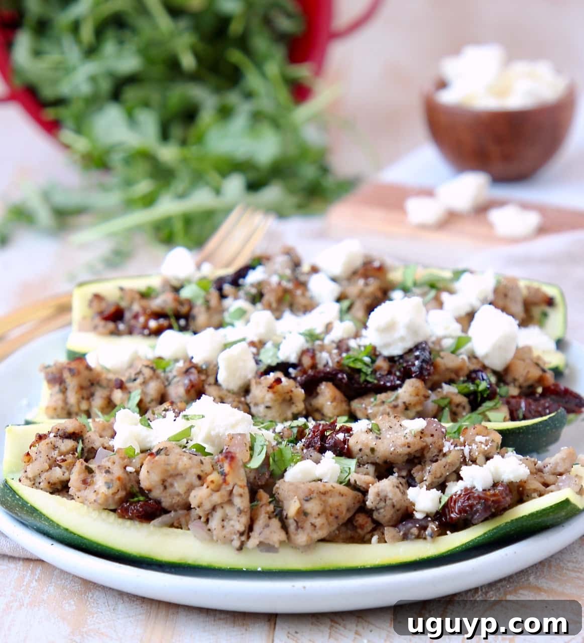 Hollowed zucchini halves generously filled with ground turkey, sun-dried tomatoes, and crumbled feta cheese on a white serving plate.