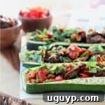 Mediterranean Tuna Salad with Roasted Red Peppers and Sun Dried Tomatoes Stuffed in Roasted Zucchini Boats on Wood Cutting Board