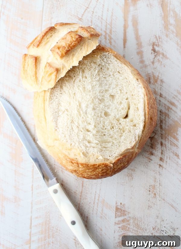 A delicious holiday party appetizer, this Baked Brie in a sourdough bread bowl is topped with buttery sweet caramelized pears and a drizzle of honey! (Visual of hollowing out bread)
