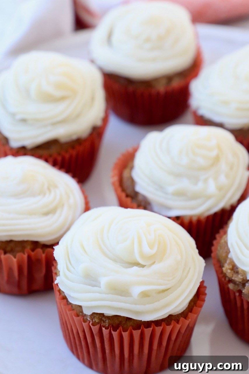 Close-up of frosted pumpkin cupcakes in orange paper liners, arranged neatly on a serving plate