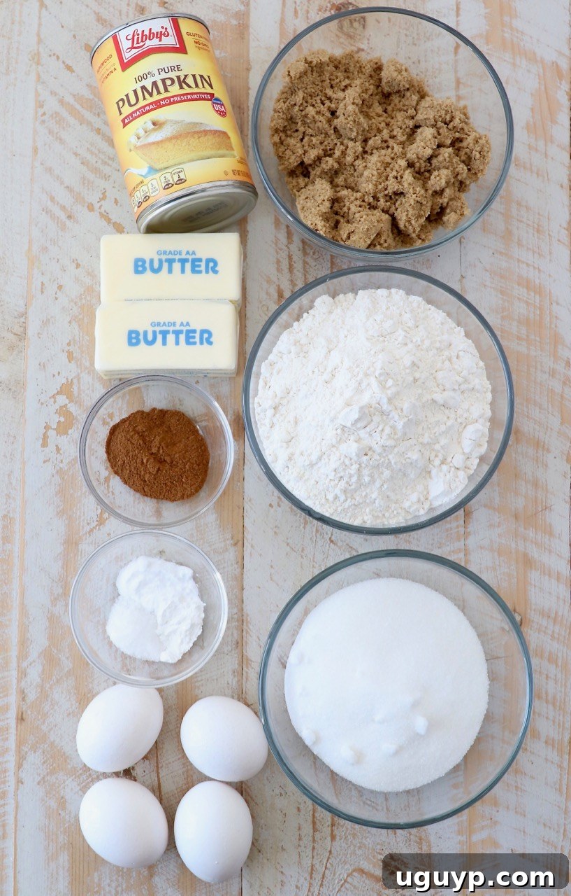 Assortment of fresh ingredients laid out for baking pumpkin cupcakes, including flour, sugars, butter, eggs, and canned pumpkin puree.