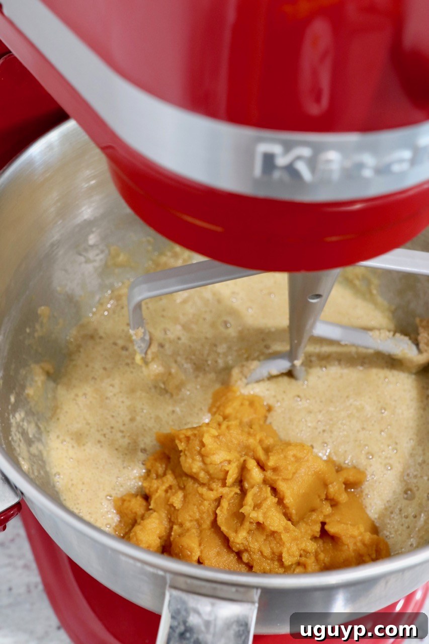 Cupcake batter in a stand mixer with pumpkin puree added