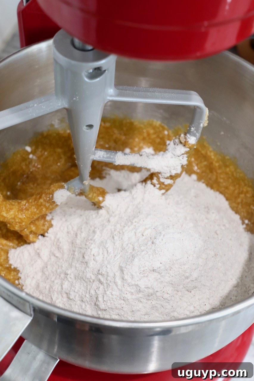 Dry flour mixture being added to the pumpkin cupcake batter in a stand mixer