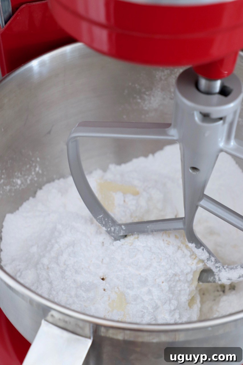 Cream cheese frosting ingredients, including softened cream cheese, butter, powdered sugar, and vanilla, in a stand mixer