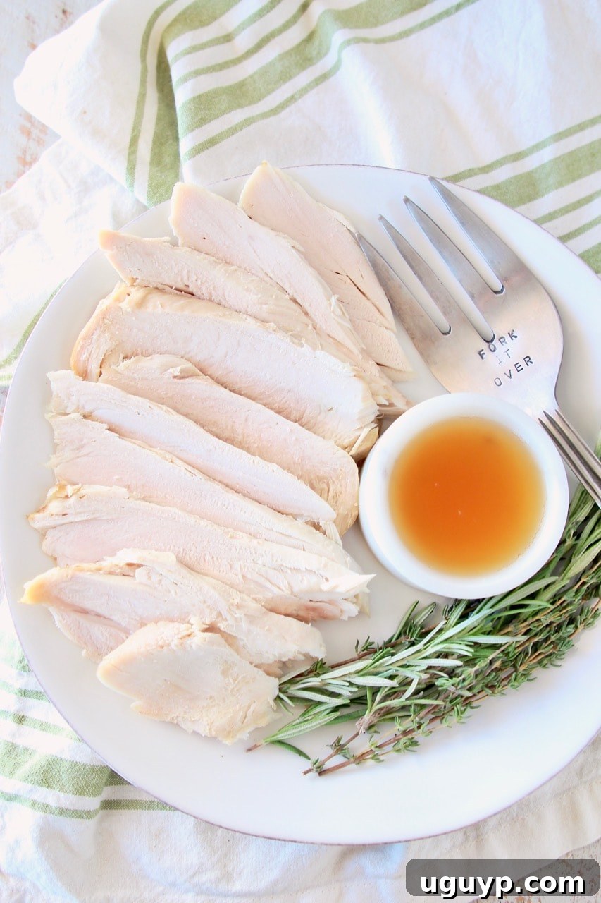 Sliced turkey breast on plate with small white bowl of apple reduction, large fork and fresh rosemary and thyme sprigs, on white and green cloth towel