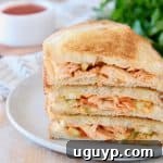 Buffalo turkey grilled cheese sandwiches, sliced in half diagonally, stacked up on white plate with fresh parsley in the background