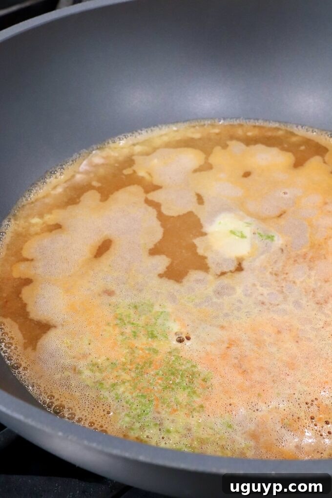 simmering broth in a large pot with lime zest, garlic and ginger