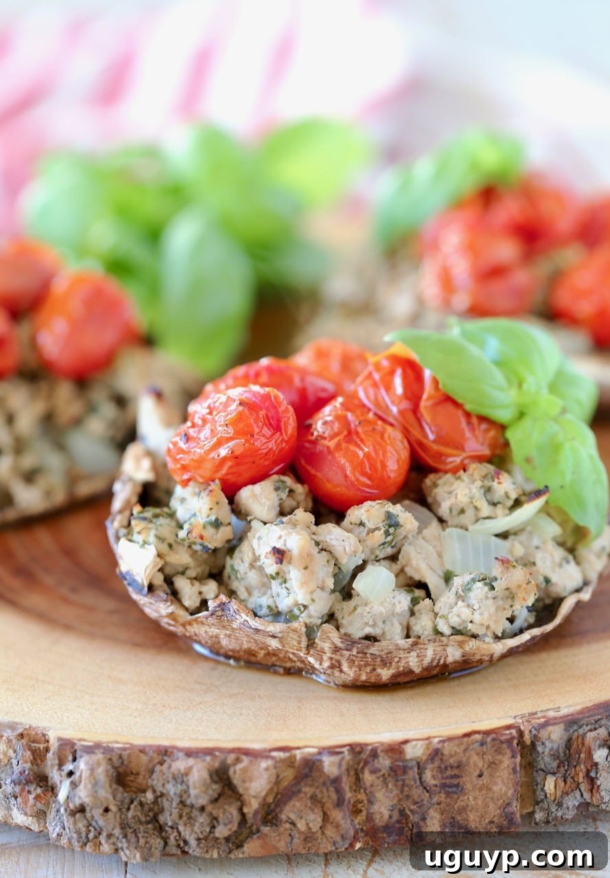 Close-up shot of Baked Italian Stuffed Portobello Mushrooms with ground turkey, vibrant cherry tomatoes, and fresh basil, resting on a rustic wooden cutting board, highlighting the savory filling and perfectly cooked mushroom texture.
