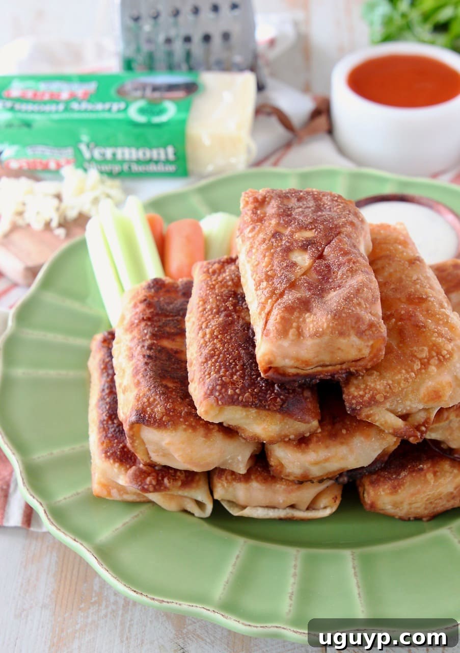 Buffalo chicken egg rolls neatly piled on a vibrant green plate, surrounded by fresh carrot and celery sticks in the background, ready to be served as a delicious appetizer.