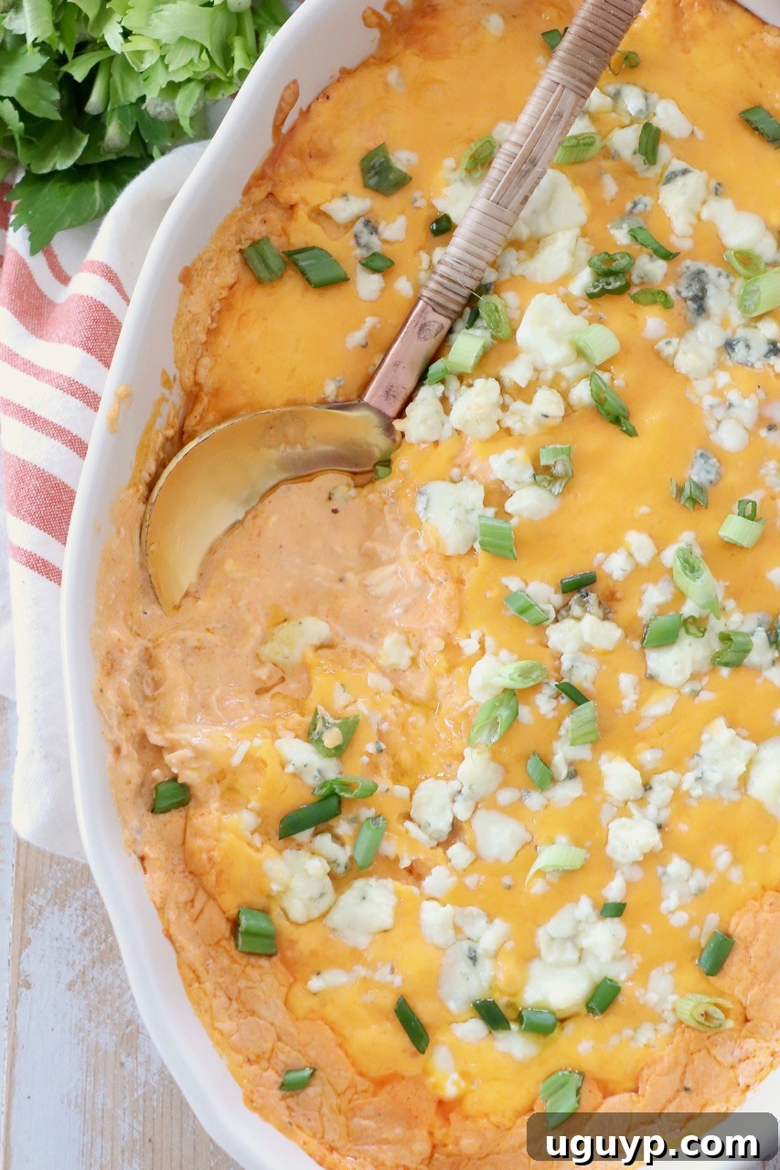 buffalo chicken dip in a baking dish with a serving spoon, ready to be enjoyed