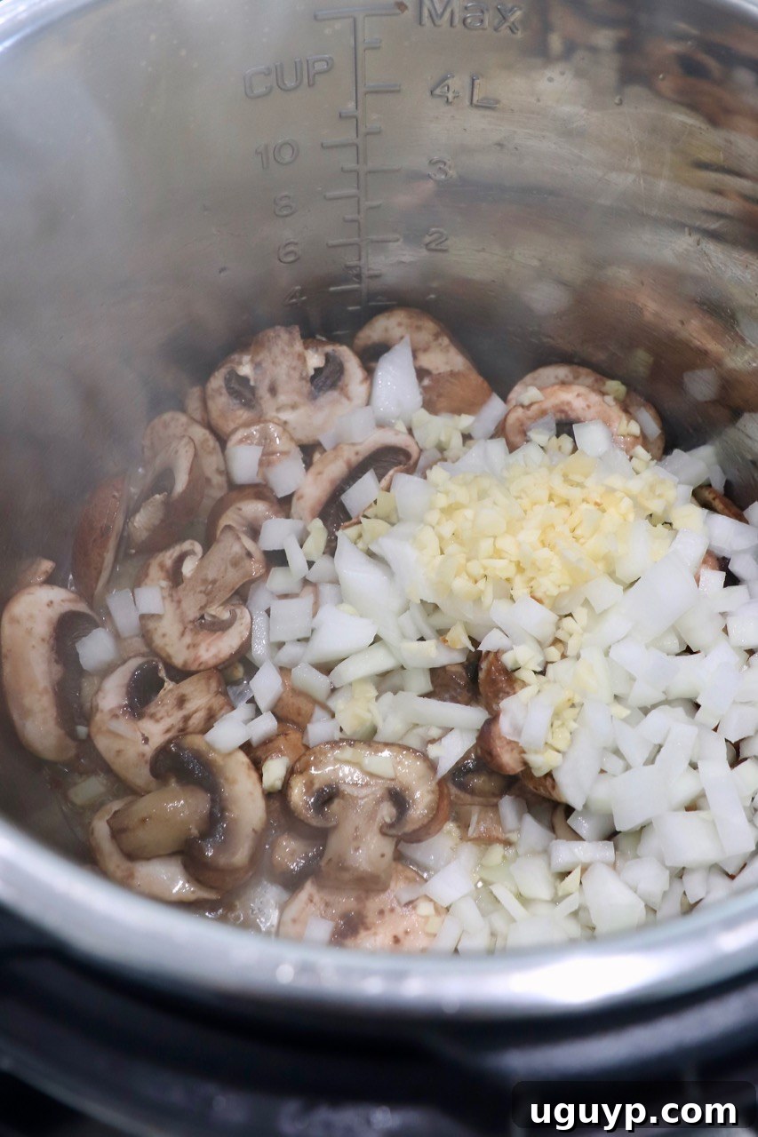 Diced onions, sliced mushrooms, and minced garlic sautéing in an Instant Pot base.