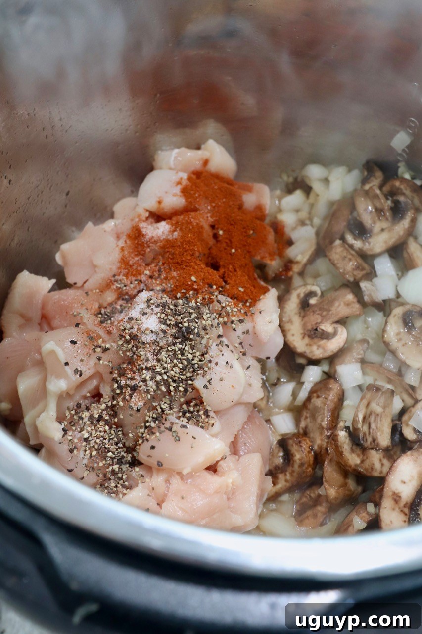 Diced chicken breasts seasoned with spices and vegetables browning in the Instant Pot.