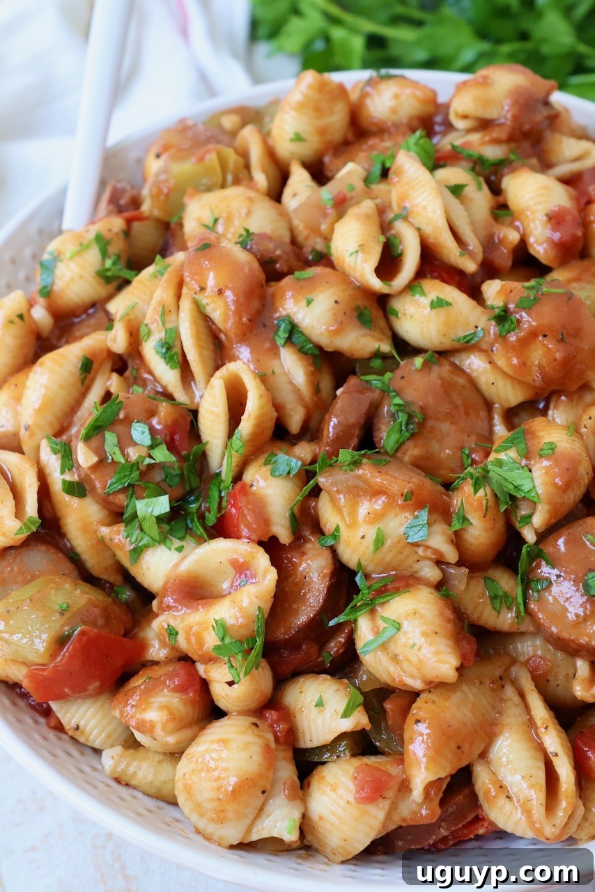 cooked pasta with sausage and bell peppers in a large white bowl