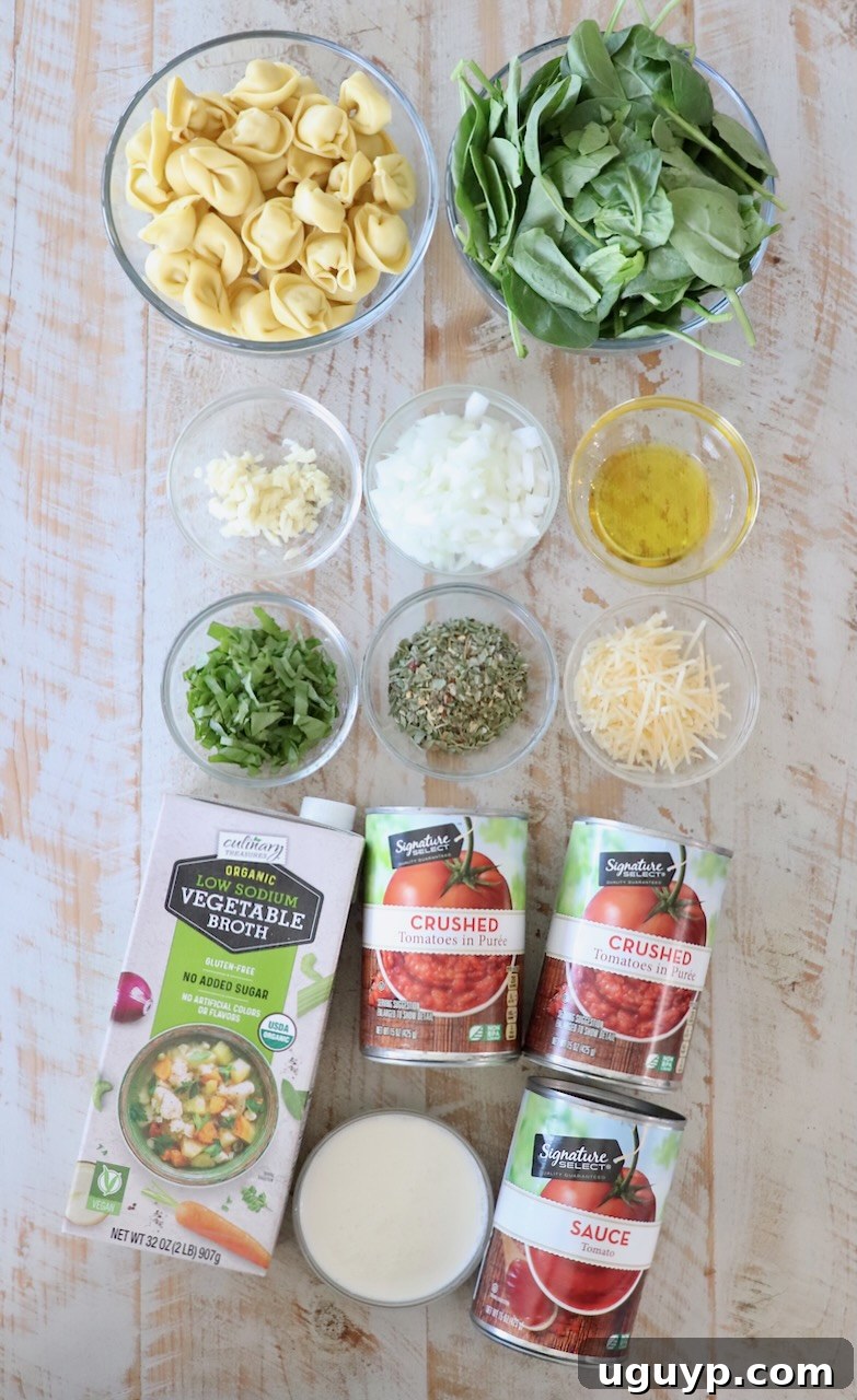 All the fresh and canned ingredients for creamy tortellini soup laid out on a white wooden board, ready for preparation.