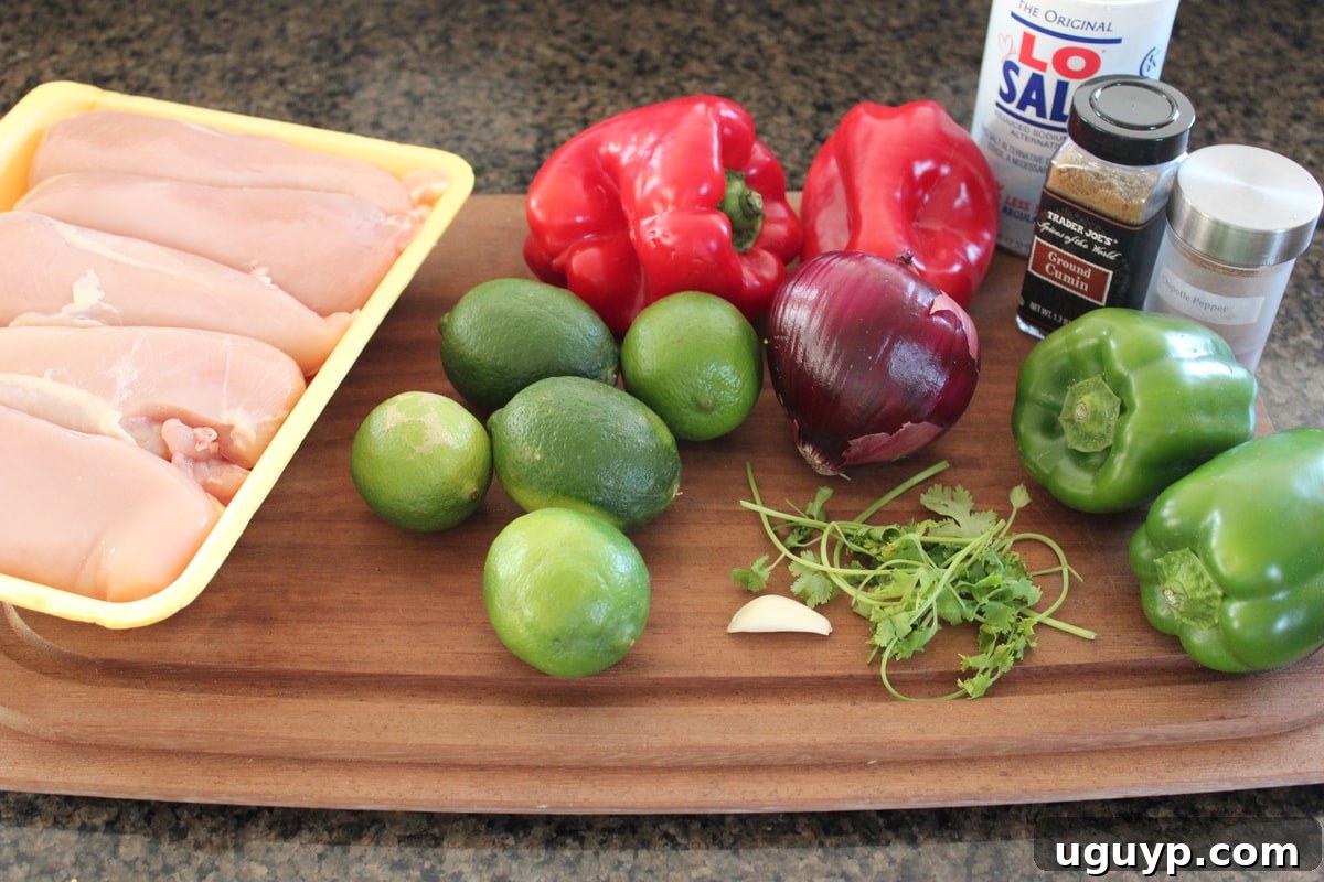Chipotle Lime Chicken Fajita Skewer Ingredients laid out on a wooden cutting board, including diced chicken, bell peppers, onions, limes, cilantro, and spices.