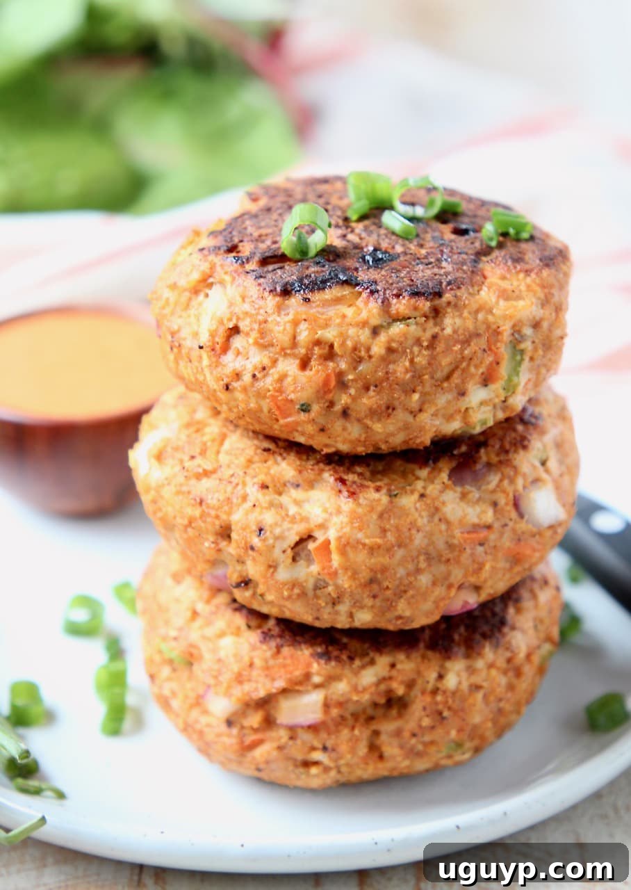 Buffalo chicken burger patties stacked on top of each other on white plate