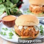 Chicken burger on bun with blue cheese crumbles and buffalo wing sauce