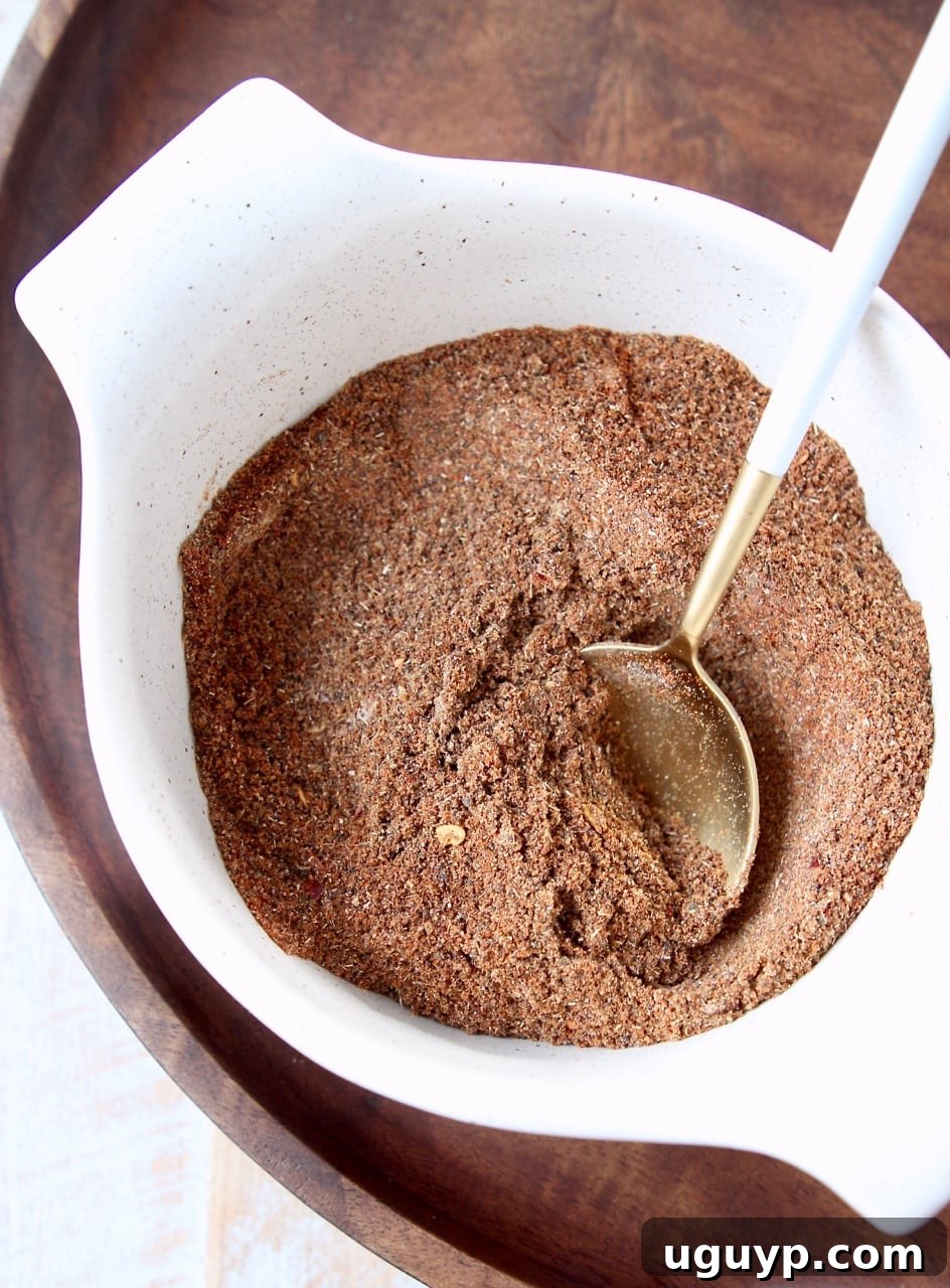 Chili seasoning blend in a white bowl with a gold and white spoon in the bowl