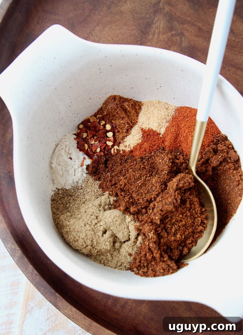 Separated spices in a bowl with a spoon, highlighting individual ingredients for chili seasoning