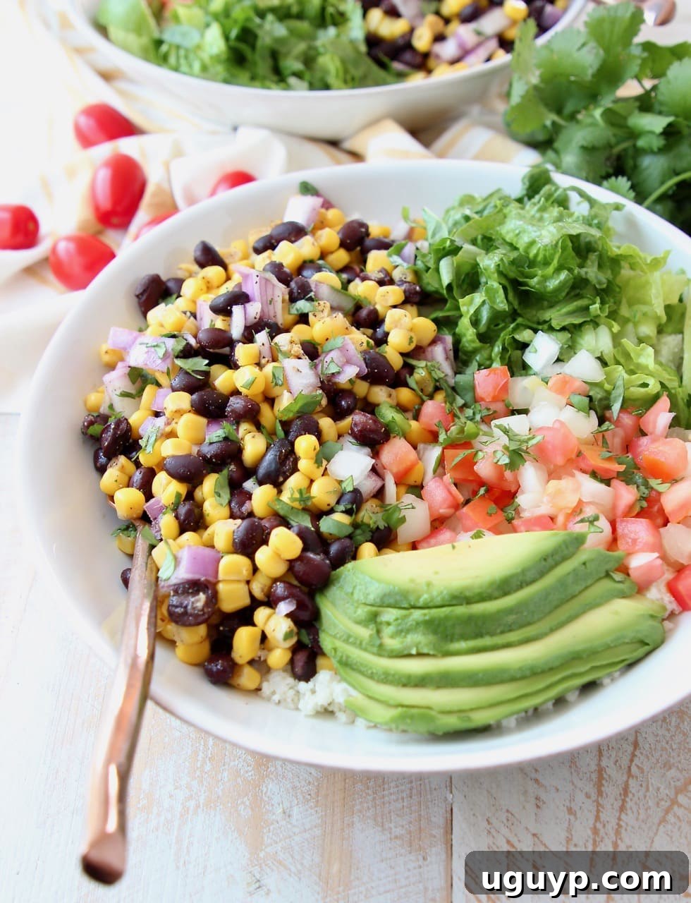 Vegan burrito bowl topped with avocado, black beans, corn, tomatoes and romaine lettuce