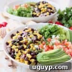 White bowl with sliced avocado, black bean and corn relish, diced tomatoes and shredded lettuce
