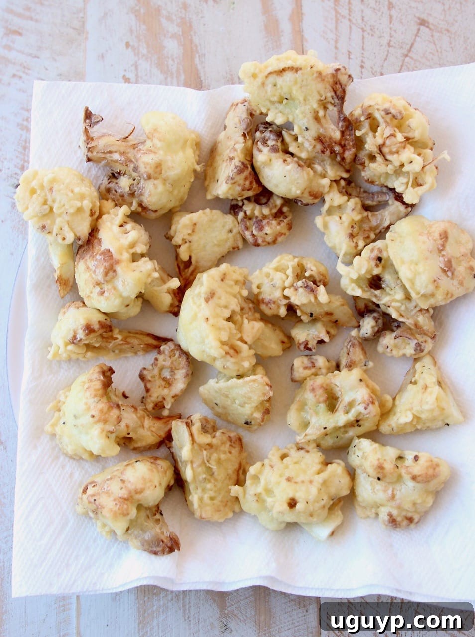Fried cauliflower pieces on paper towel lined plate