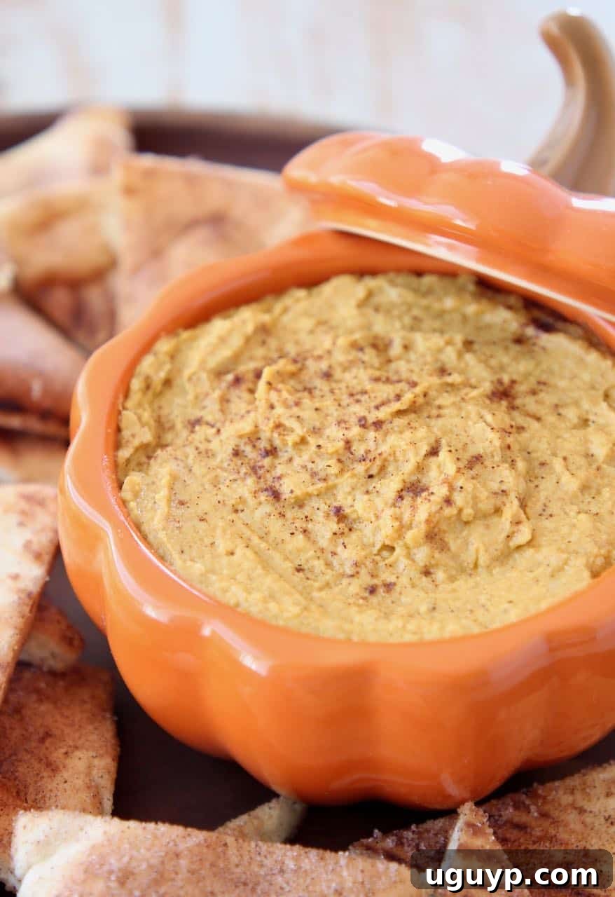 Pumpkin hummus served in a festive orange pumpkin-shaped serving bowl