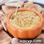 Pumpkin hummus in orange bowl with gold spoon