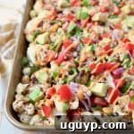 Cauliflower nachos on gold sheet pan topped with diced tomatoes and avocado