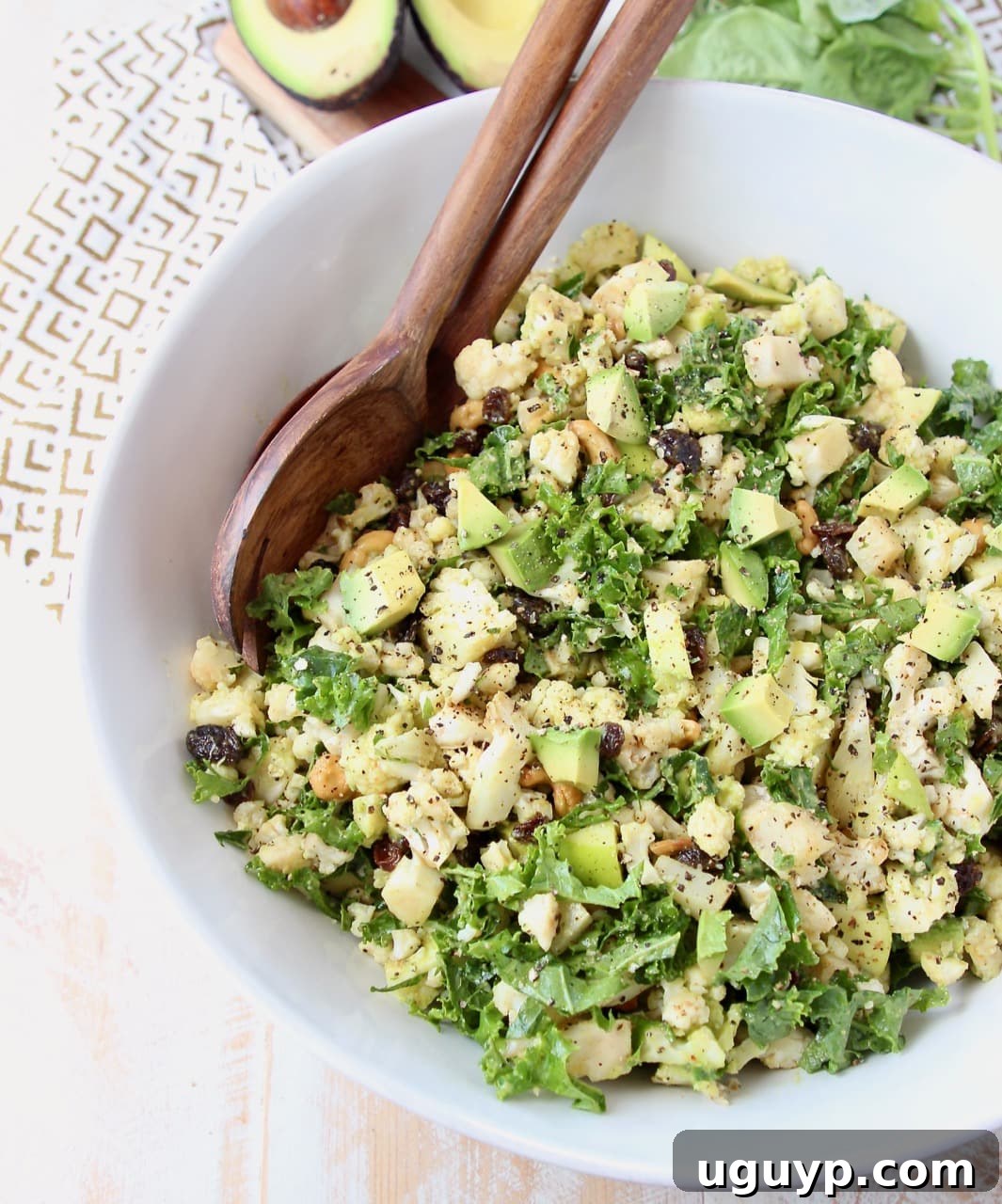 Overhead shot of cauliflower salad with chopped kale and avocado in large white bowl