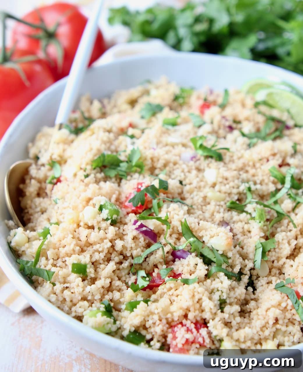 A vibrant bowl of Mexican Vegetarian Couscous, garnished with fresh cilantro and lime wedges.