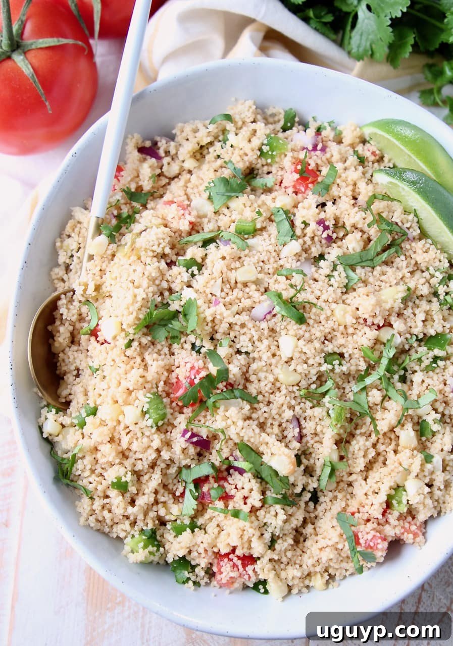 Close-up overhead view of Mexican couscous, garnished with fresh cilantro, diced tomatoes, and bright lime slices.