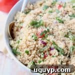 Couscous in bowl with white and gold spoon, topped with chopped cilantro