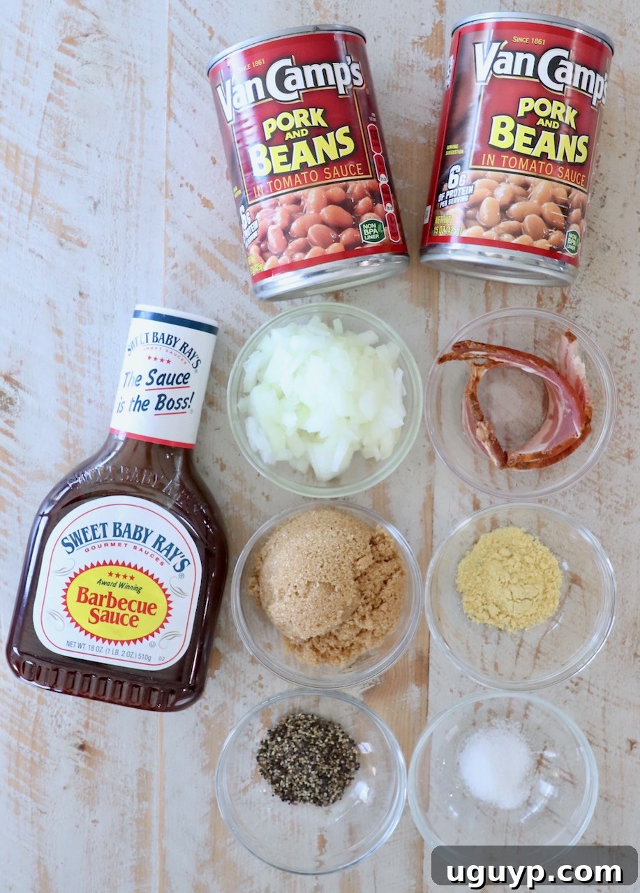 A rustic white wooden board displaying all the fresh ingredients needed for homemade BBQ baked beans: cans of pork and beans, strips of bacon, brown sugar, a bottle of BBQ sauce, a diced onion, and small bowls of ground mustard, salt, and pepper.