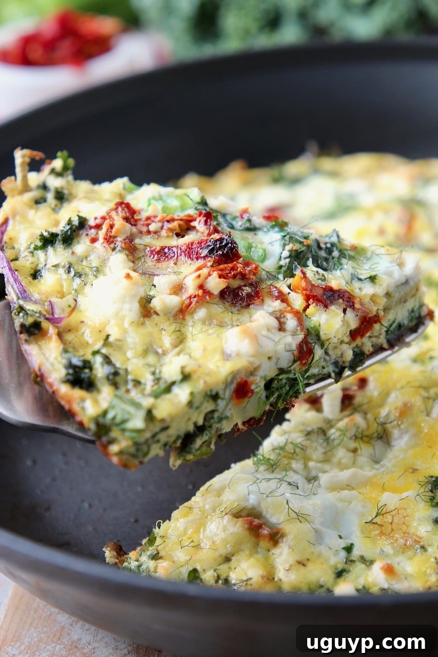 Slice of vibrant vegetable frittata being lifted from a cast iron skillet with a spatula, showcasing the colorful ingredients.