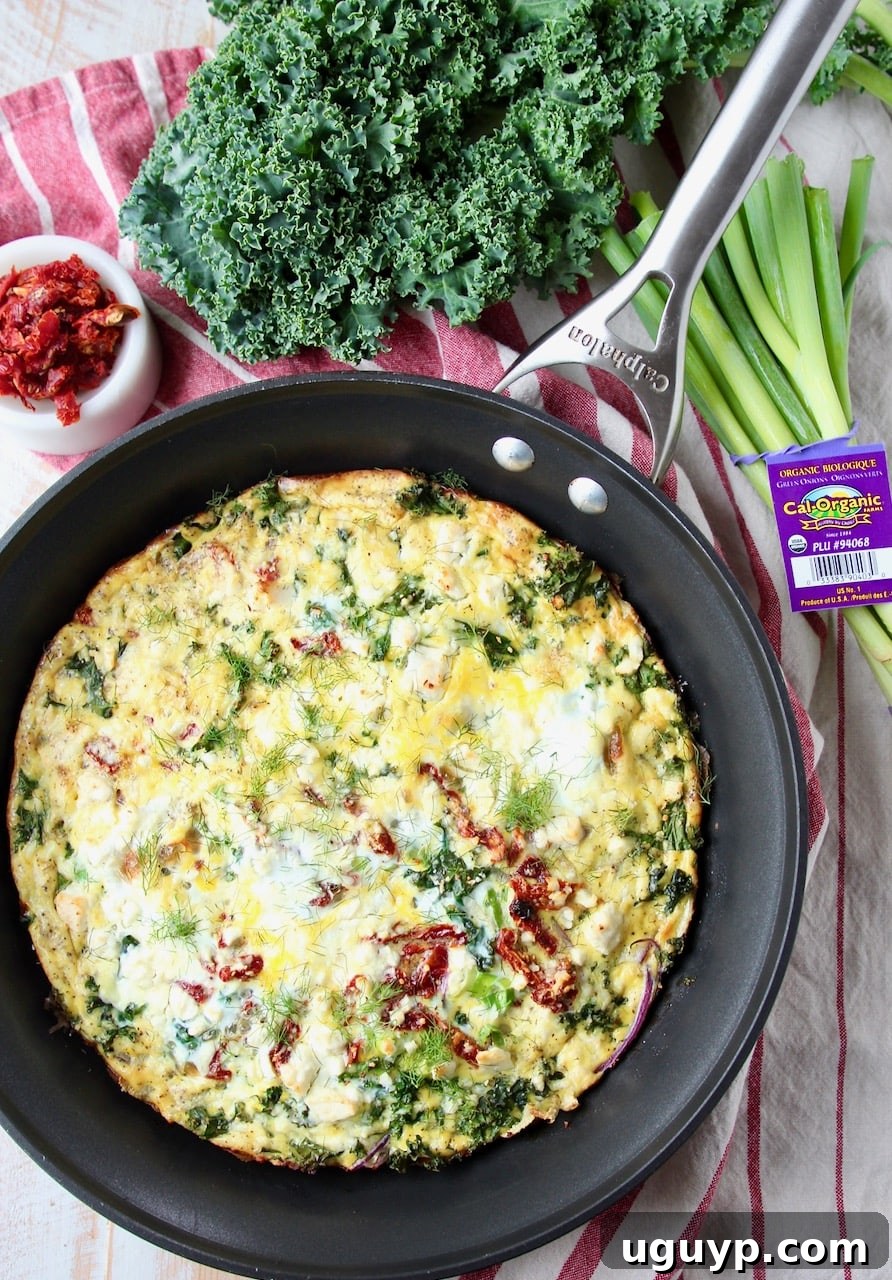 A vibrant vegetarian frittata sits in a cast iron skillet, garnished with fresh kale and green onions arranged artfully on the side.