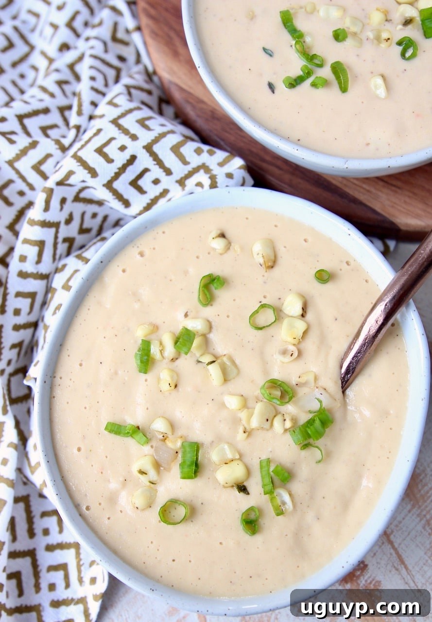 A beautifully presented bowl of creamy corn soup, with a polished copper spoon resting alongside, highlighting its rich texture.