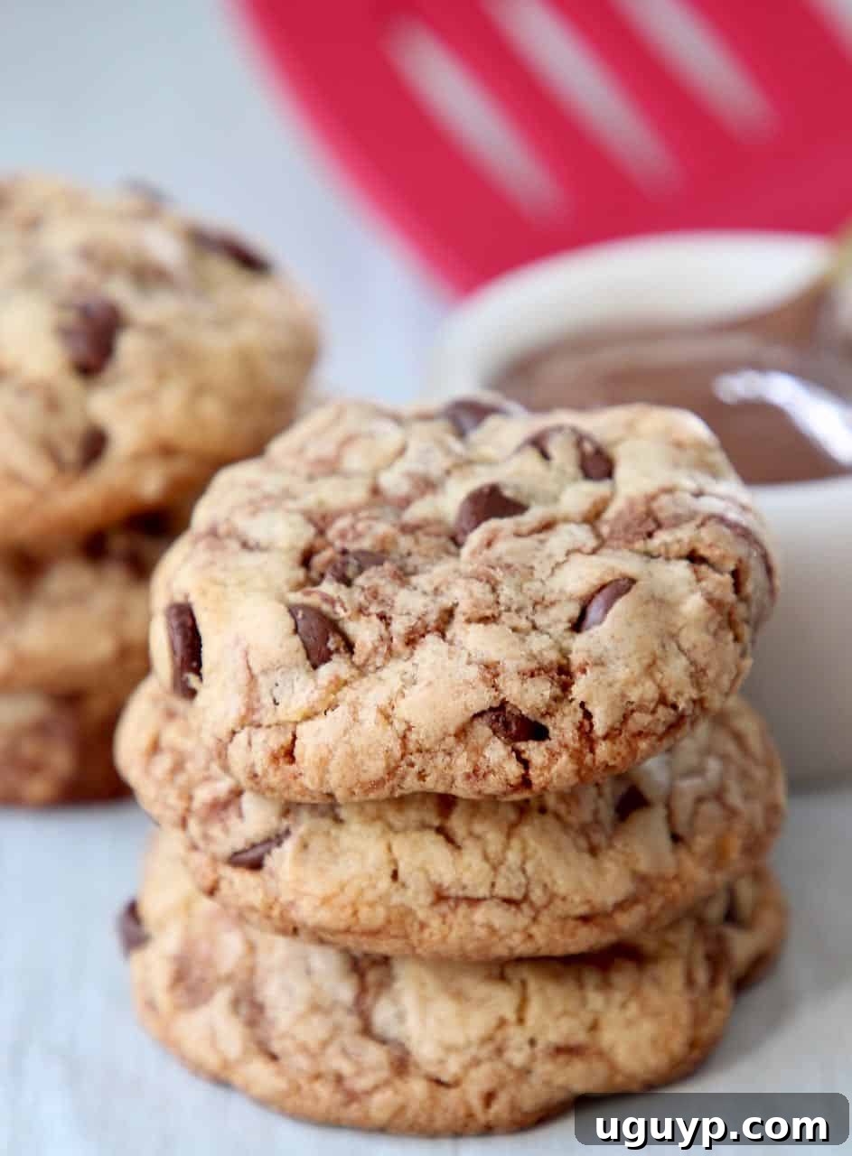 A stack of golden-brown Nutella chocolate chip cookies on a white plate, showcasing their perfect shape and inviting texture.