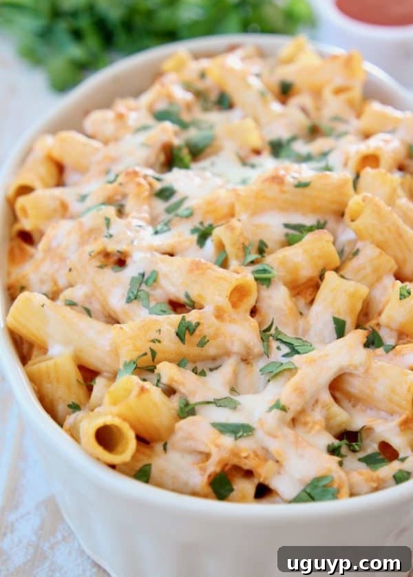 Baked rigatoni with melted cheese, served hot in a rustic casserole dish, hinting at a comforting meal.