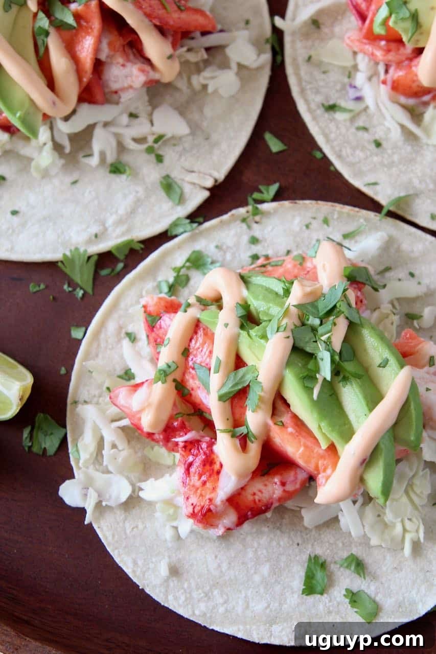 Freshly prepared lobster tacos on a rustic wooden tray, garnished with lime wedges and avocado slices, showcasing the vibrant ingredients.